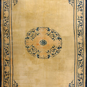 A beige rug features a navy blue and peach medallion and intricate blue scrollwork borders.