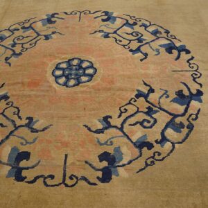 A beige rug displays a pink central medallion with swirling dark blue and light blue decorative motifs.