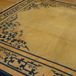 Mustard yellow area rug with detailed navy and coral borders resting on rustic light hardwood floors.