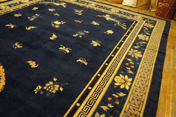 Dark blue rug with scattered yellow floral motifs and a detailed geometric border on wood floors.