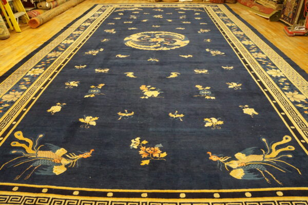 Deep blue area rug featuring gold bird and floral designs, laid on bright yellow wood flooring.