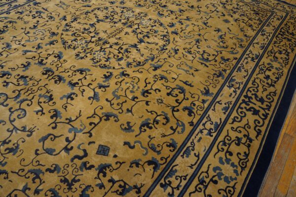 Gold rug with dark and light blue scrolling vine patterns and bordered edges on wood flooring.