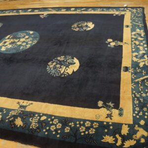 Navy rug featuring circular gold and teal floral medallions bordered by wide tan panels on light wood flooring.