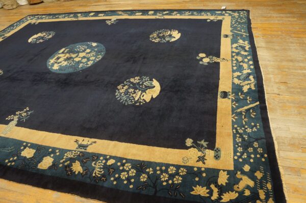 Navy rug featuring circular gold and teal floral medallions bordered by wide tan panels on light wood flooring.