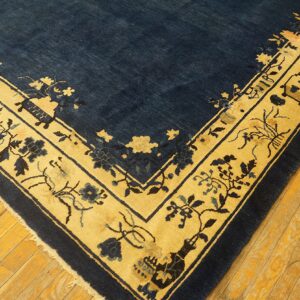 Close-up of a blue and gold patterned rug on aged, narrow, yellow-toned wood flooring.