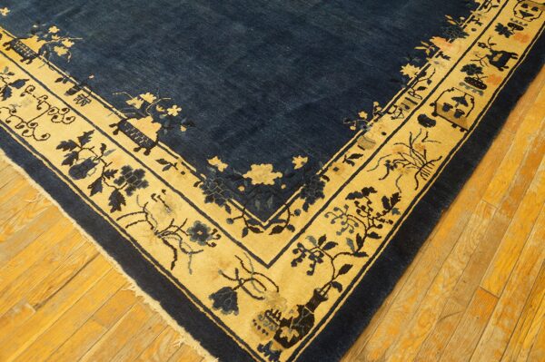 Close-up of a blue and gold patterned rug on aged, narrow, yellow-toned wood flooring.