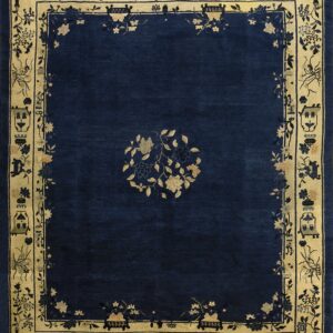 A navy blue rug features a central gold floral motif and an elaborate beige border with detailed patterns.