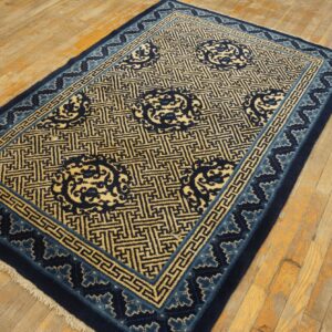 Navy blue and light gold rug featuring geometric patterns and round medallions on distressed wood flooring.