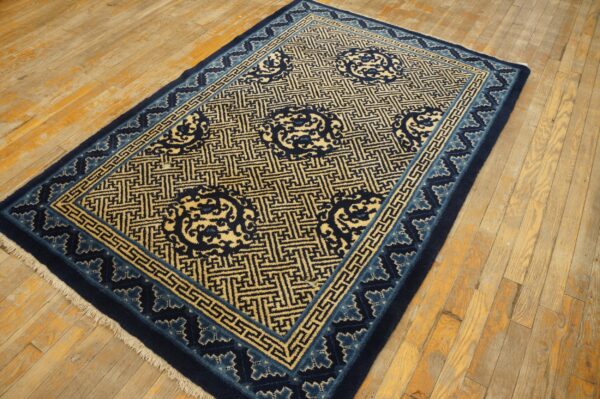 Navy blue and light gold rug featuring geometric patterns and round medallions on distressed wood flooring.