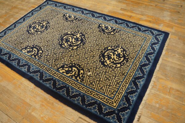 Navy blue and cream geometric rug with stylized medallions rests on a distressed wood floor.
