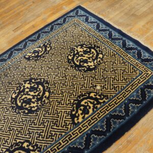 Dark blue and golden yellow geometric rug lies on light brown distressed wood flooring.