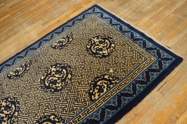 Dark blue and golden yellow geometric rug lies on light brown distressed wood flooring.