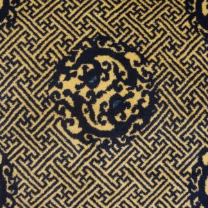 Navy blue and yellow rug displaying dense interlocking geometric patterns and a partial curved central design.
