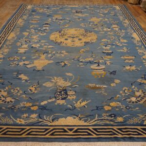 Blue rug featuring yellow and navy botanical, vase, and medallion patterns on wood floors.