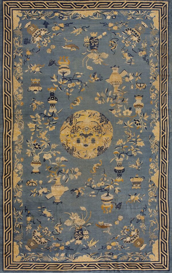 Muted blue rug patterned with tan and navy flowers, vases, and a large circular central medallion.