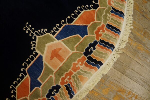 A plush, deep blue rug with colorful geometric and wave patterns rests on worn light wood flooring.