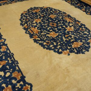 Plush beige rug featuring a large navy and terracotta floral medallion and border on wood flooring.