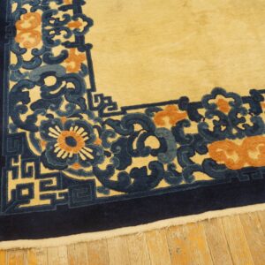 Yellow rug with high-contrast navy, blue, and orange floral scroll border on wood floors.