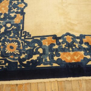 Close-up of a high-pile rug border in ivory, deep blue, light blue, and peach colors on wood flooring.