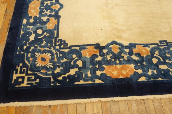 Close-up of a high-pile rug border in ivory, deep blue, light blue, and peach colors on wood flooring.