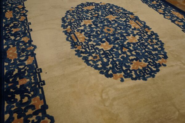 Cream rug with complex indigo and apricot floral medallion and scrollwork borders.
