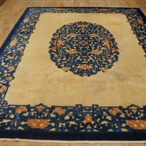 Cream rug featuring a large navy and rust medallion and wide scrolling border on wood floors.