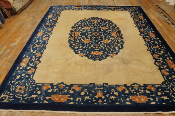 Cream rug featuring a large navy and rust medallion and wide scrolling border on wood floors.