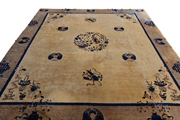 Tan rug with navy blue floral and bird motifs, surrounded by a wide brown outer border.