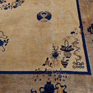 Beige field rug with scattered blue botanical and vase designs and a wide brown patterned border.