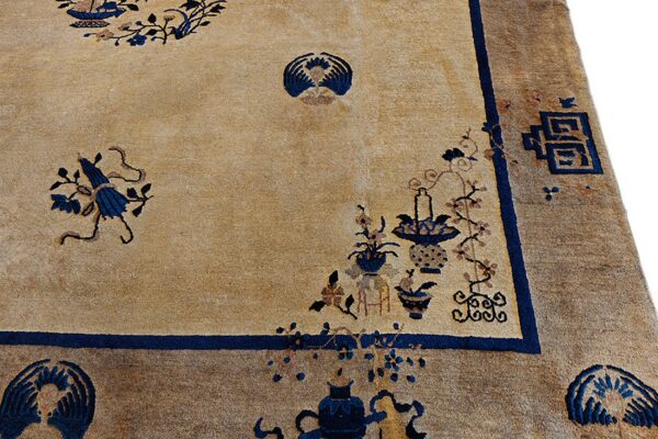 Beige field rug with scattered blue botanical and vase designs and a wide brown patterned border.