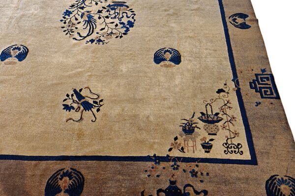Tan field rug with ornate blue bird, flower, and vase patterns bordered in solid brown and blue.