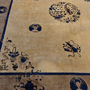 Tan rug with navy floral medallions and vase motifs bordered by a wide contrasting taupe band.