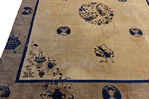 Tan rug with navy floral medallions and vase motifs bordered by a wide contrasting taupe band.