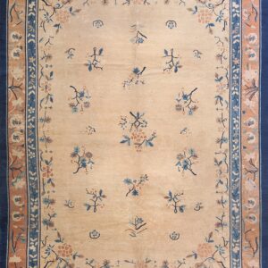 Light beige rug with scattered blue and peach floral designs framed by layered navy blue and tan borders.