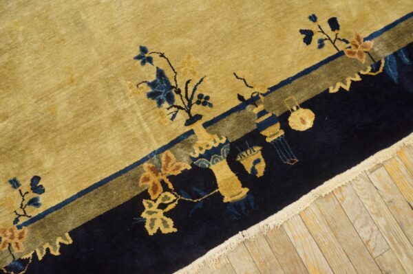 Golden yellow rug with a contrasting navy border and patterned botanical elements rests on light hardwood.