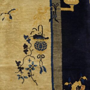 Plush gold and blue patterned rug detail next to a wide navy border on light wood plank flooring.