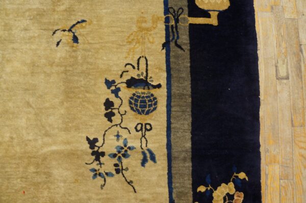 Plush gold and blue patterned rug detail next to a wide navy border on light wood plank flooring.