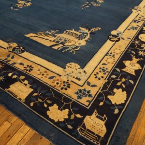 Corner of a deep blue rug featuring tan and navy intricate border patterns, lying on hardwood flooring.