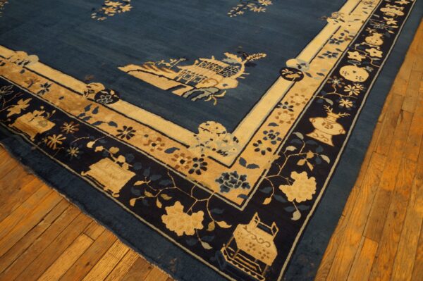 Corner of a deep blue rug featuring tan and navy intricate border patterns, lying on hardwood flooring.