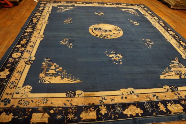 Deep blue rug with cream borders and landscape designs, including a circular central medallion, placed on hardwood.