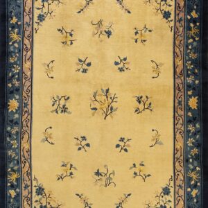 A pale yellow rug featuring scattered blue and gold floral sprays and a wide dark blue border.