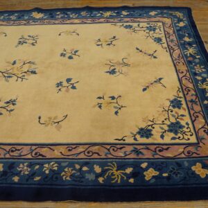 Low-pile rug in cream with scattered blue florals and a wide dark blue butterfly border on wood floors.