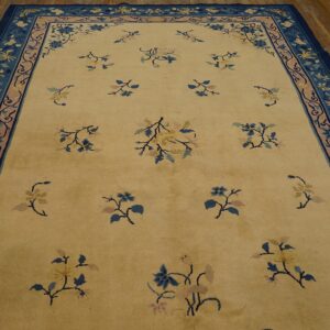 A creamy yellow rug with scattered blue and pink floral motifs, framed by multi-layered borders in navy and dusty rose.
