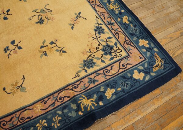 Yellow rug with blue, pink, and gold floral patterns rests on aged wooden floorboards.
