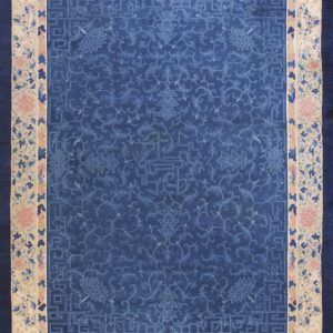 Ornamental dark blue rug with a tone-on-tone floral pattern and a wide cream border featuring pink flowers.