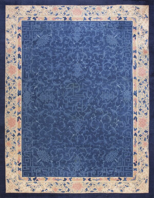 Ornamental dark blue rug with a tone-on-tone floral pattern and a wide cream border featuring pink flowers.