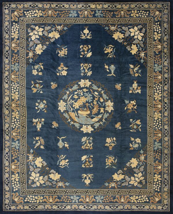 Ornate dark blue rug featuring a central medallion with a bird, surrounded by tan and pale blue florals.