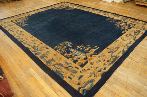 Deep blue rug with an expansive tan border featuring detailed pagodas and florals on light wood floors.