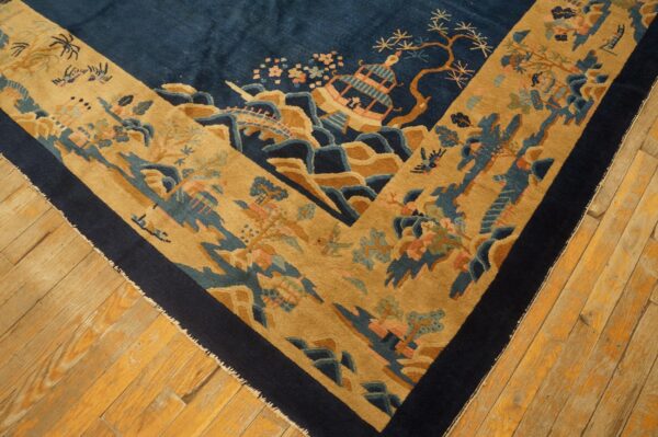 Plush navy and tan rug with an oriental landscape design lays on worn light plank wood floors.