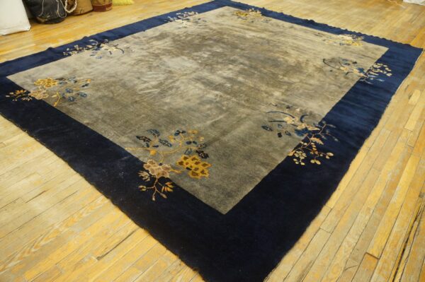 Area rug with a dark navy border and a gray field featuring gold and blue floral motifs.